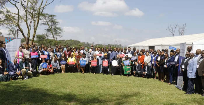 Participants to the event pose for a picture with the project banner in a garden