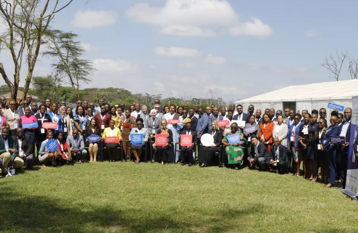 Participants to the event pose for a picture with the project banner in a garden