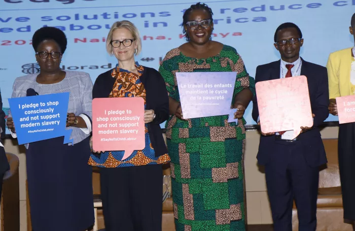 High level representatives from the ILO and Kenya pose holding in their hands banners stating quotes against child labour