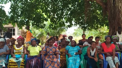 Female community members seat under a tree