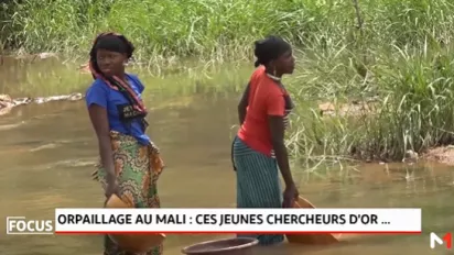 Women with their feet under water collect water for gold mining with buckets in a gold mining site