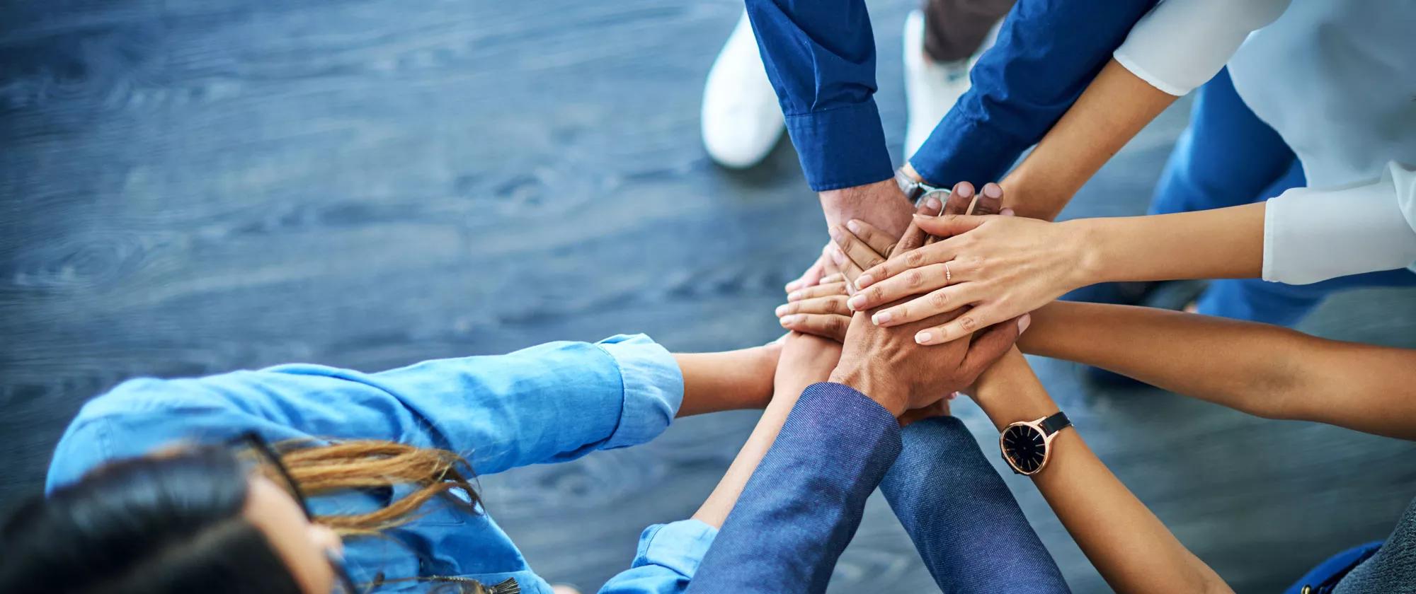 Group with hands together symbolizing collaboration, teamwork, partnership and goals